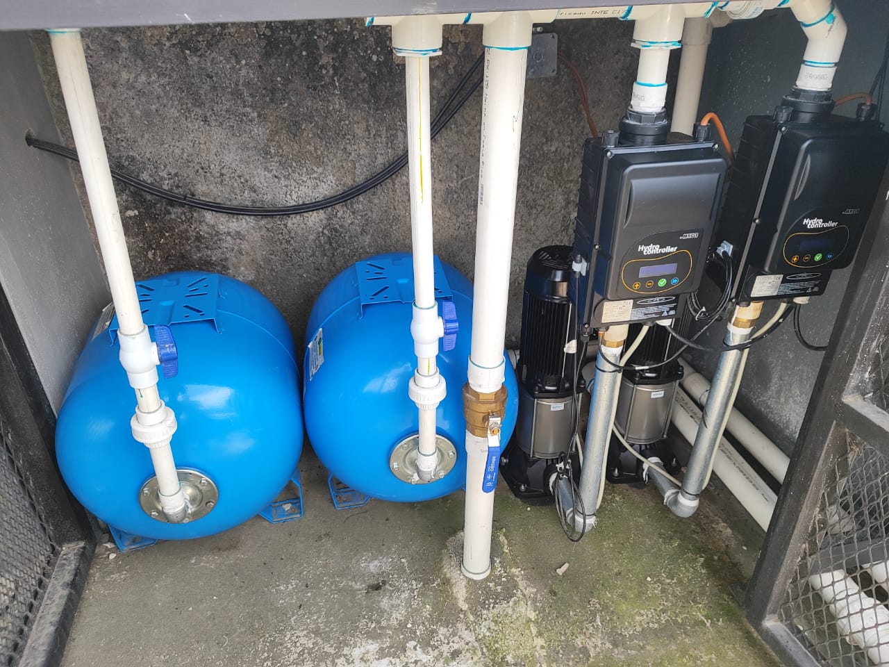 Sistema duplex instalado en cementerio de Cartago en espacio de concreto con tanques hidroneumáticos celestes y bombas color plateadas y tuberia visible